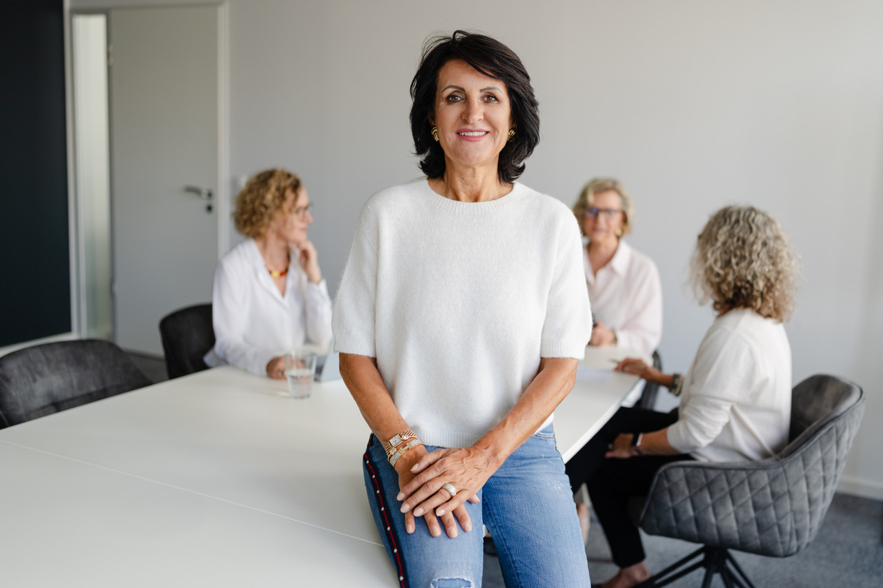 Barbara Rottwinkel-Kröber, Karrierecoach für Frauen 40+, steht im weißen Shirt vor einer Dreigruppe Frauen und lächelt